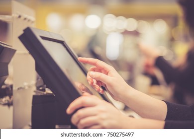Young woman hands counting / entering discount / sale to a touchscreen cash register, market / shop (color toned image)