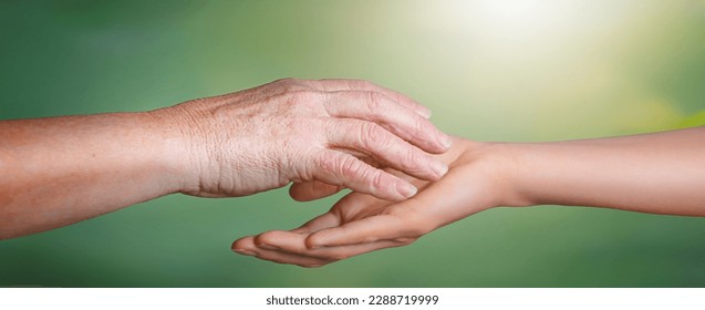 Young woman hands holding elderly hands with clipping path on green autumn background.