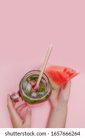 Young woman hands holding freshly squeezed watermelon lemonade of citrus fruits. Female with mason jar full of cold cocktail, mint leaves. Pink background, copy space, close up. - Shutterstock ID 1657666264