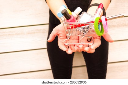 Young Woman Hands Holding Trolley With Makeup Objects And Gadgets - Female Vanity And Shopping Addiction - Girl With Colorful Beauty Products On Wooden Background - Light Pink Vintage Filter 