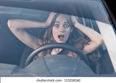Young woman with hands on eyes sitting scared in car