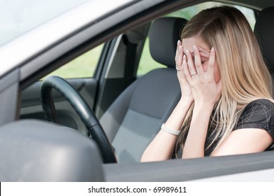 Young woman with hands on eyes sitting depressed in car