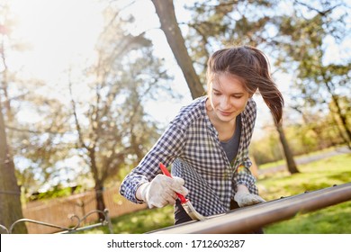 Young woman as a handyman when painting and renovating a table in the garden in summer - Powered by Shutterstock