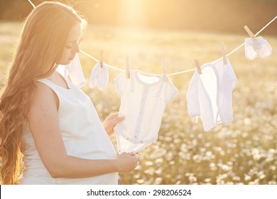 Young Woman Hanging Up Baby Laundry