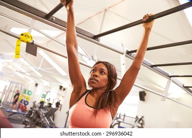 Young Woman Hanging From Monkey Bars At A Gym