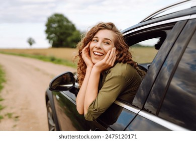 Young woman  hanging out of car with hands up enjoying fresh summer wind in nature. Summer trip. Lifestyle, travel, tourism, nature, active life - Powered by Shutterstock