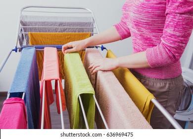 A Young Woman Hangs Clothes On The Dryer For Clothes After Washing In A Washing Machine. Device For Drying Laundry After Washing. Women's Hands And Wet Clothes