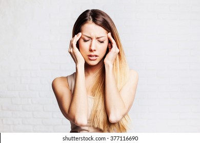 Young woman has headache isolated  on gray background
