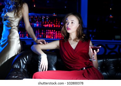 young woman has a rest with an alcoholic drink, second woman on a background - Shutterstock ID 102800378