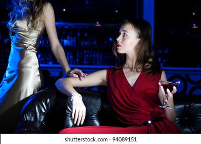 young woman has a rest with an alcoholic drink, second woman on a background - Shutterstock ID 94089151