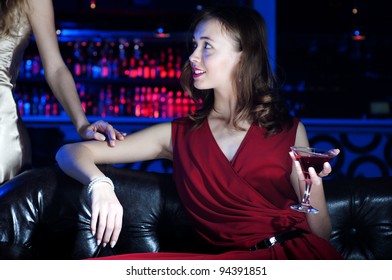 young woman has a rest with an alcoholic drink, second woman on a background - Shutterstock ID 94391851