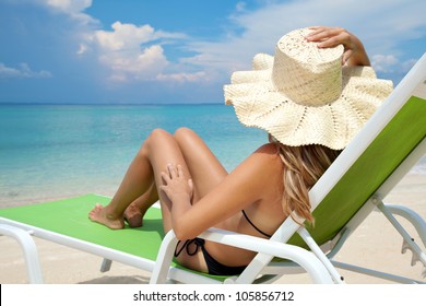 Young woman with hat relaxing on a deck chair