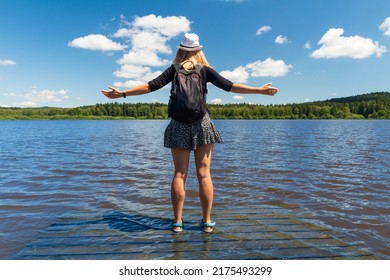 Young woman with hat standing on wooden platform in pond from back, educational trail Olsina. Sumava reserve, Czech summer landscape