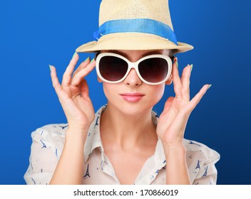 Young woman in hat and sunglasses , isolated on blue background