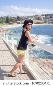 Young Woman With Hat And Sunglasses Walking By The Public Swimming Pool At Bronte Beach In Sydney Australia