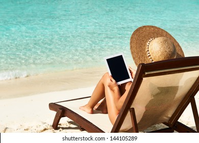 Young woman in hat with tablet pc at the beach - Powered by Shutterstock