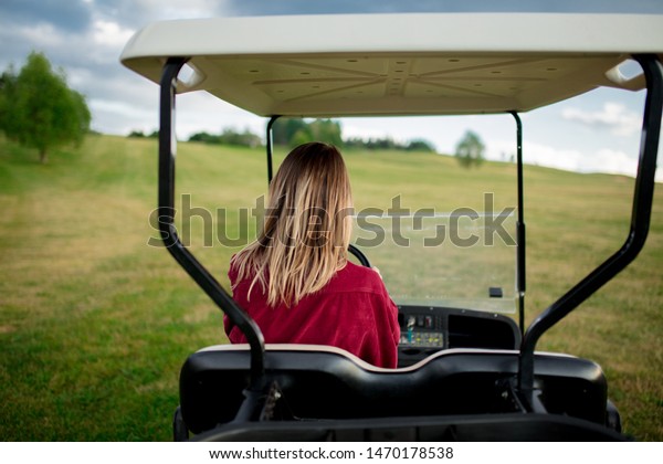 Young woman have a fun with golf buggy car on a\
field in mountains