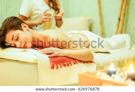 Young woman having back oil therapy massage in spa resort hotel salon - Female enjoying relaxing thai massage - Body care, skin care, wellness and chilling concept - Focus her eye - Warm filter
