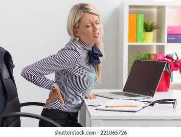 Young Woman Having Back Pain While Sitting At Desk In Office