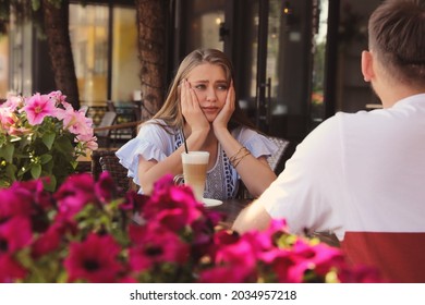 Young Woman Having Boring Date With Guy In Outdoor Cafe