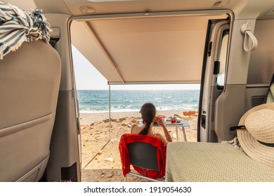 A young woman having breakfast in her caravan observing a good view of the beach - Shutterstock ID 1919054630