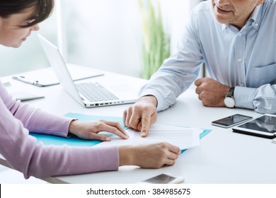 Young woman having a business meeting with an executive in his office, he is pointing on a contract and giving explanations