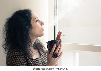 Young Woman Having A Coffee And Cigarette Break Indoors In A Smoking Room