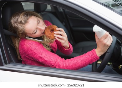 Young Woman Having Coffee And Doughnut In Her Car