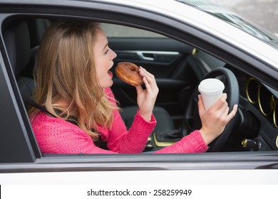 Young Woman Having Coffee And Doughnut In Her Car