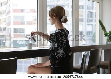 Young woman having coffee near window in cafe	