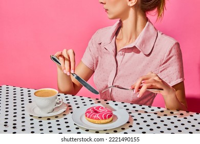 Young woman having delicious breakfast with donut and coffee over pink background. Yummy. Vintage, retro style interior. Food pop art photography. Complementary colors. Copy space for ad, text