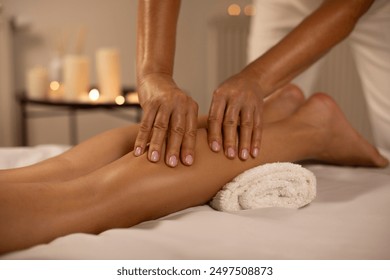 Young woman having feet and legs massage in spa salon, masseur kneads leg of young lady, serene atmosphere with candles - Powered by Shutterstock