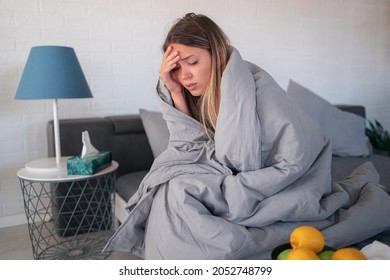 Young woman having a flue. She is sitting on bed at home and feeling tired of it all