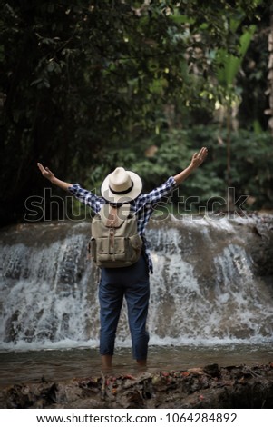 Young woman having fun under waterfalls in the forest