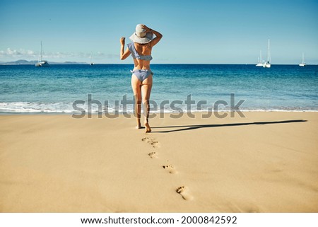 Young woman having fun walking by the beach during summer vacation - Focus on girl back