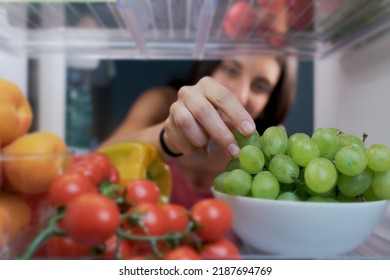 Young woman having a healthy snack, she is taking fruit in the fridge, POV shot from inside of the fridge - Powered by Shutterstock