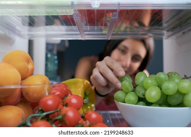 Young Woman Having A Healthy Snack, She Is Taking Fruit In The Fridge, POV Shot From Inside Of The Fridge