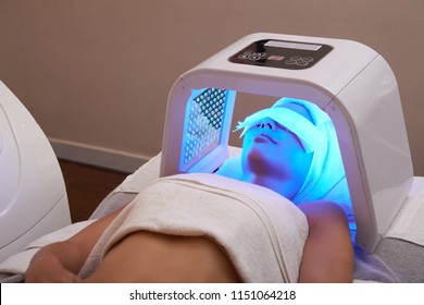 Young woman having LED light facial treatment in beauty salon