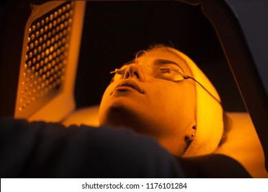 Young Woman Having LED Light Facial Treatment In Beauty Salon