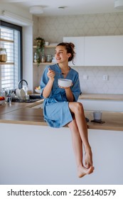 Young woman having muesli for breakfast in her kitchen, morning routine and healthy lifestyle concept. - Shutterstock ID 2256140579