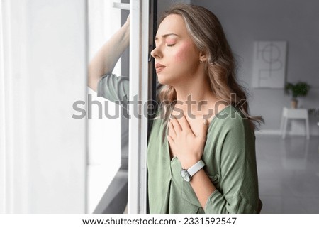 Young woman having panic attack near window