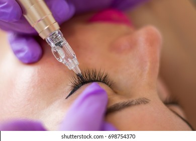 Young Woman Having Permanent Makeup Eyeliner In Beautician Salon