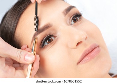 Young Woman Having Professional Eyebrow Correction Procedure In Beauty Salon