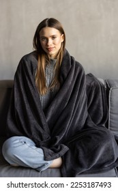 Young woman having a rest. Wrapped up in white blanket and drinking coffee in warm atmosphere, copy space - Shutterstock ID 2253187493