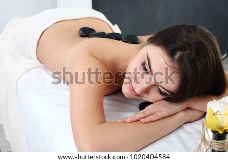 Young woman having stone massage in spa salon. Healthy lifestyle.