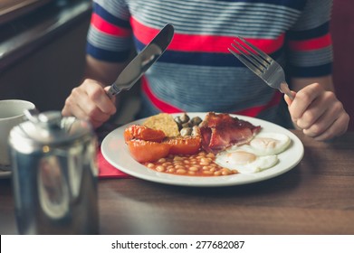 A Young Woman Is Having A Traditional English Breakfast In A Diner