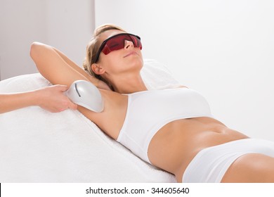 Young woman having underarm laser hair removal treatment in salon