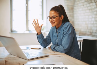 Junge Frau mit Videoanruf über Laptop im Büro