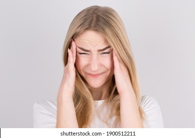 Young woman with a headache holds her temples with her hands. Health, migraine and headache concept