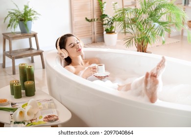 Young woman with headphones and cup of coffee taking bath at home - Powered by Shutterstock